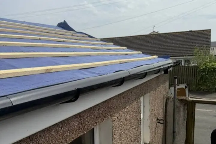 New white uPVC fascia board and black gutter fitted below new roofing membrane and battens