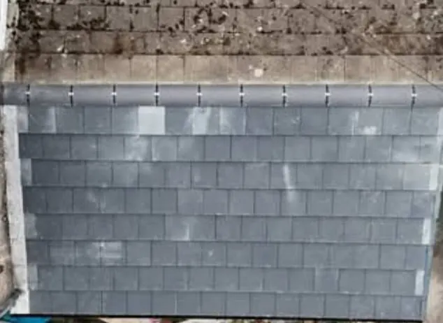 New grey roof tiles and a dry ridge on the re-roofed side of the extension, seen from above